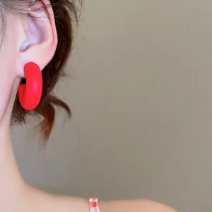 Minimalist red C-shape acrylic earrings with a matte frosted finish on model
