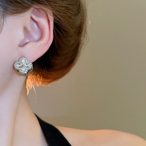 Close-up of diamond-studded clover earrings on model showing exquisite craftsmanship