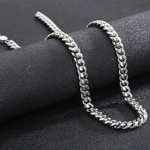 Detailed close-up of polished silver stainless steel Cuban link chain on a textured stand