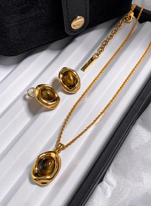 Detail view of gold-plated oval tiger eye necklace and earrings set in gift box