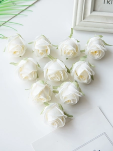 Ten white artificial silk roses with green sepals arranged in a heart shape on a desk