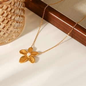 Detail eines filigranen 18K Gold Blumenanhängers mit Perle an einer feinen Halskette