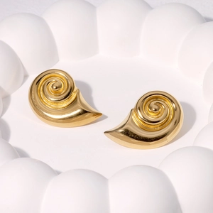 Golden spiral conch shell stud earrings in stainless steel on a white decorative plate