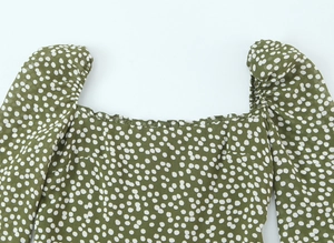 Détail de l'encolure carrée à volants sur une robe verte à pois blancs