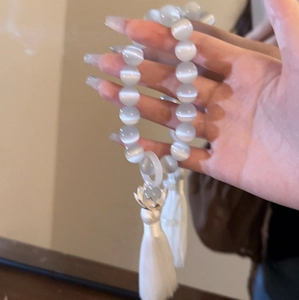 Detailed close-up of white opal beads and lotus flower pendant with tassel