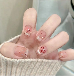 Gros plan d'ongles cat eye roses avec paillettes argentées et nœud perlé rouge