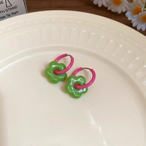 Detailed macro view of dopamine-style green enamel flower pendants on pink hoops