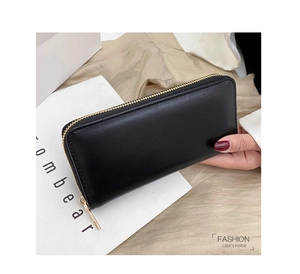 Nahaufnahme einer schwarzen Leder-Clutch mit goldenem Reißverschluss vor weichem Hintergrund