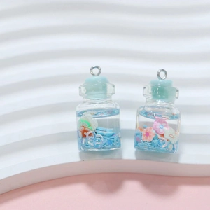 Close-up of miniature blue driftwood bottle pendants with pink flowers and metallic rings
