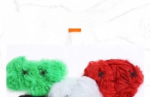 Detailed view of colorful Halloween spider webs in green red white and black with plastic spiders