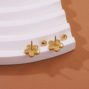 Detail of gold floral screw back earrings on a textured brown leather backdrop