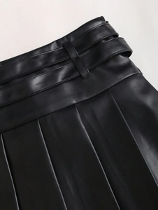 Detailed close-up of high-waist black PU leather pleated skirt waistband and stitching