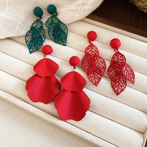 Detailed macro view of matte flower and leaf tassel earrings in green and red