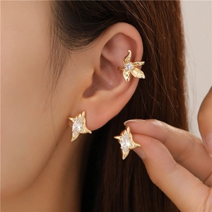 Detail of gold star studs and leaf ear cuff set with white zircons on model ear