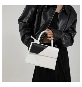Détail d'un sac à main chic noir et blanc avec texture crocodile porté par un mannequin