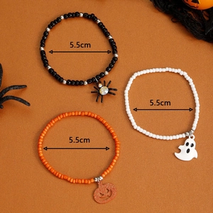 Halloween beaded bracelet set with ghost, pumpkin, and spider charms on autumn background