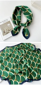Detailed view of dark green silk scarf featuring gold fan patterns and twill satin texture