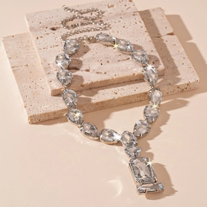 Macro detail of silver necklace with teardrop crystals and emerald-cut stones