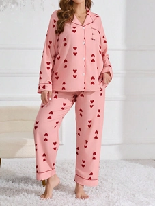 Detail of pink pajama set with red heart prints, notched collar, and contrast piping