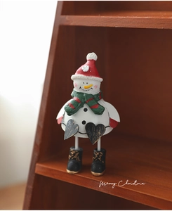 Detail of painted metal snowman figurine with Merry Christmas text on rustic wood