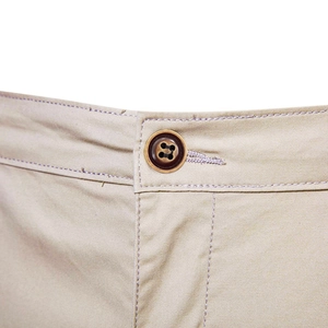 Detailed close-up of the waist button and reinforced stitching on khaki cotton shorts