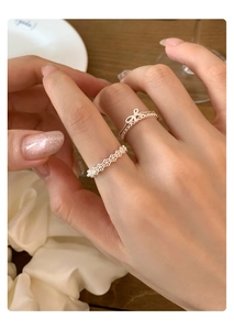 Detail of silver bow and lace rings on finger in an elegant French style setting