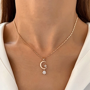 Detail of gold crescent moon and star pendant necklace set with clear gemstones