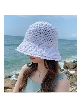 Detailed close-up of white crochet texture on a stylish summer straw bucket hat