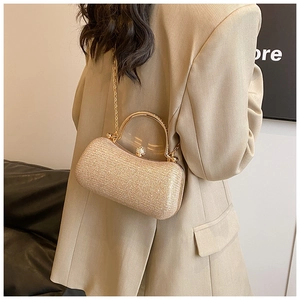 Detail of champagne gold evening clutch bag with metal handle and diamond clasp closure