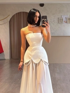 Detail of white satin dress featuring waist pearl beading and airy tulle skirt
