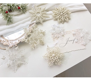 Detailed macro of white and silver glitter snowflake ornaments on green pine branches
