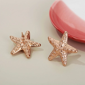 Detailed close-up of rose gold starfish earrings with textured surface and secure backs