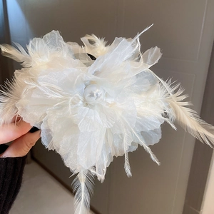 Detailansicht der weißen Organza-Blumen-Haarklammer mit Federn und eleganter Perle