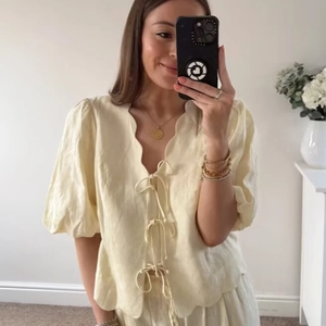 Haut jaune pâle pour femme avec nœuds frontaux, manches bouffantes et bords festonnés