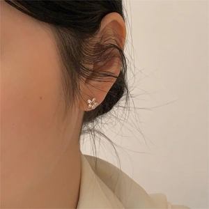 Close-up of minimalist 925 silver flower stud earring worn on a female ear
