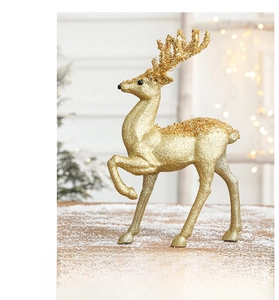 Detail of golden glitter reindeer statue with sequins on a snowy wooden surface