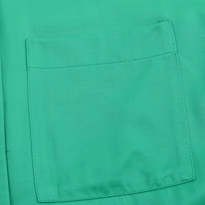 Detail shot of square pocket and fine stitching on bright green satin casual shirt