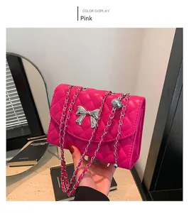 Detailed view of pink quilted handbag with silver bow detail and metal chain strap