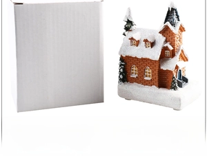 Detailed view of resin Christmas house ornament with snow effect and its white packaging box