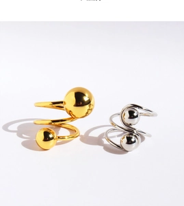 Macro detail of spiral ring with polished gold and silver spherical ends on white back