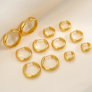 Macro shot of various sizes of polished gold titanium steel hoop earrings on beige fabric