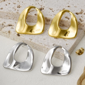 Detailed view of oval gold and silver stainless steel earrings on stone background