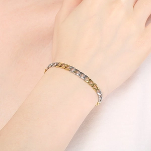 Close-up of two-tone gold and silver Cuban link chain bracelet on a model wrist