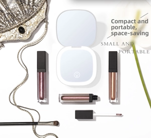 Flat lay of white portable LED makeup mirror with liquid lipsticks on a white background