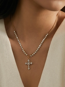 Close-up of gold-plated cross necklace with sparkling rhinestones and mixed chain detail