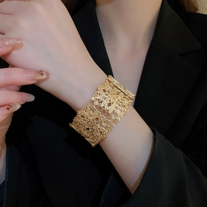 Vue détaillée d'un bracelet manchette doré filigrané aux motifs de papillons et de fleurs