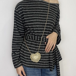 Detail of a golden heart-shaped rhinestone mini crossbody bag with a metallic chain strap