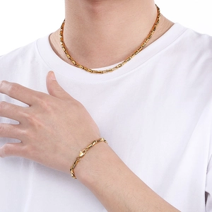 Gold titanium steel link necklace and bracelet set worn on a plain white T-shirt