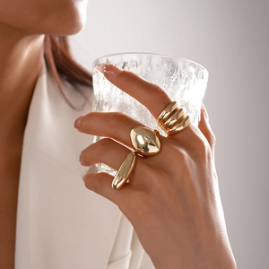 Detailed view of three polished gold rings featuring oval bean and multi-layer wrap designs