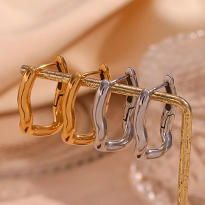 Irregular wavy U-shaped earrings in gold and silver finish on a display stand